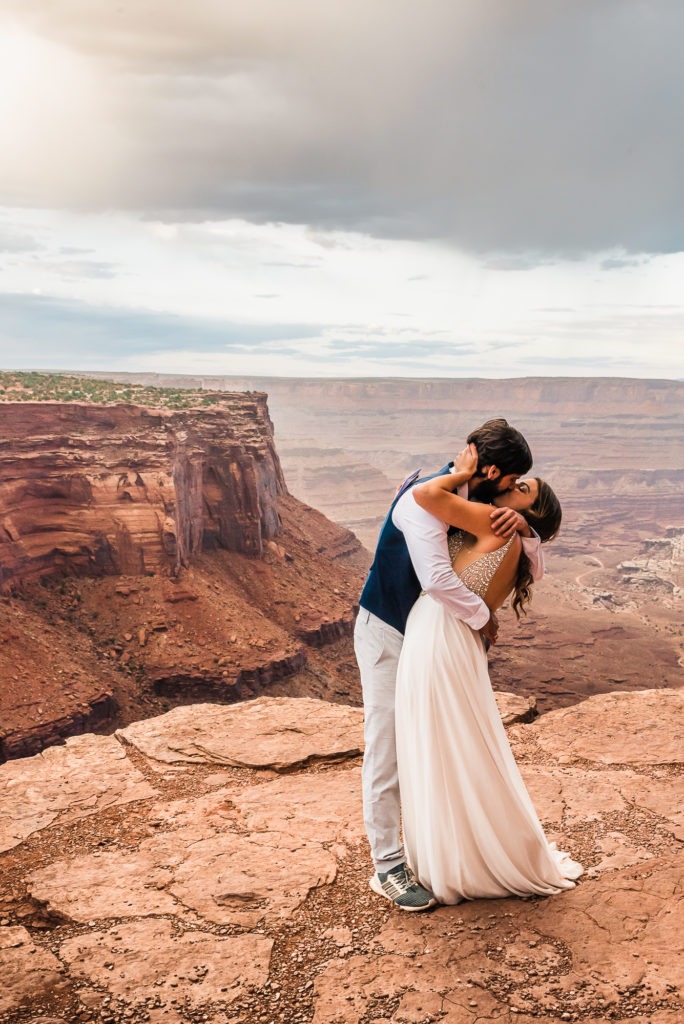Moab wedding. The couple enjoy their first cliff with never-ending canyon views.