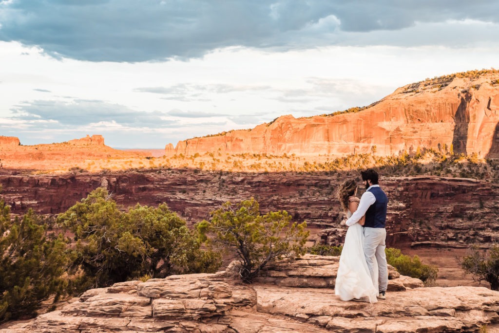 Epic Moab elopement. The rocks light up as the sun begins to set and the couple enjoy a cuddle after sharing their vows.