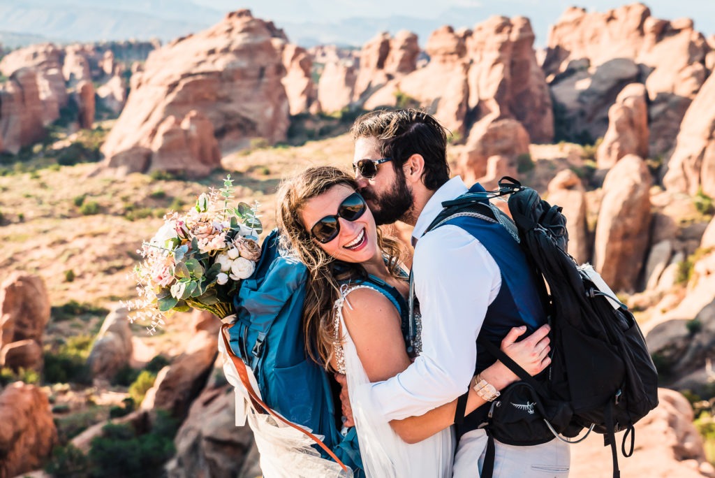 A hiking wedding in Moab. Sunglasses on, backpacks on and huge smiles!