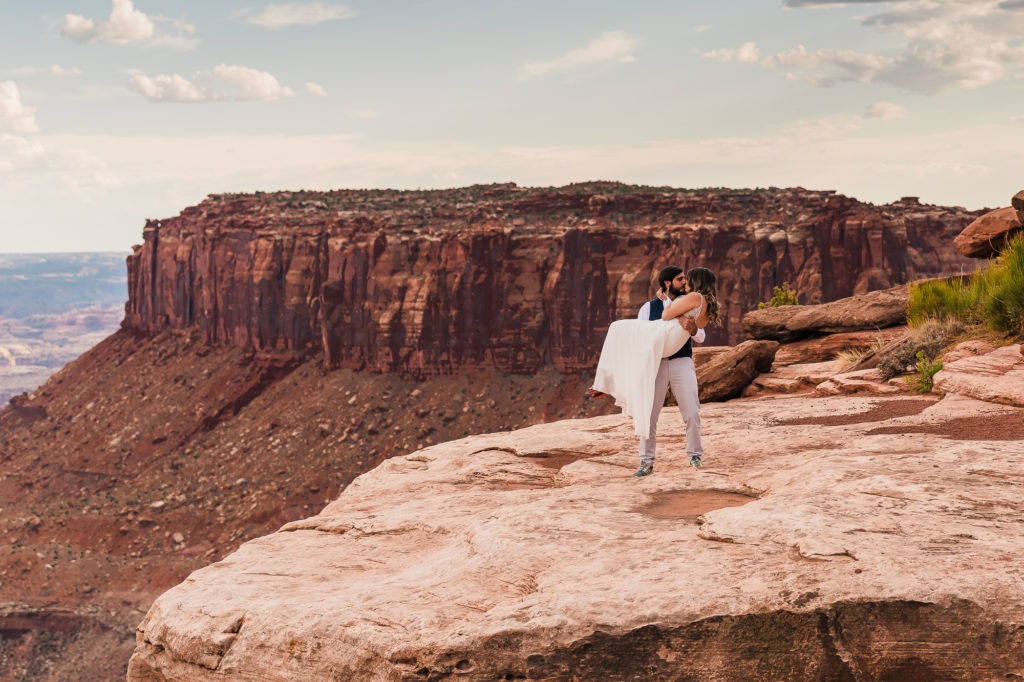 Utah wedding, Moab. The groom sweep his bride of her feet and gives her a big kiss.