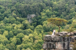 Forest wedding in Tennessee. The couple dance under a tree on a dramatic grey cliff.