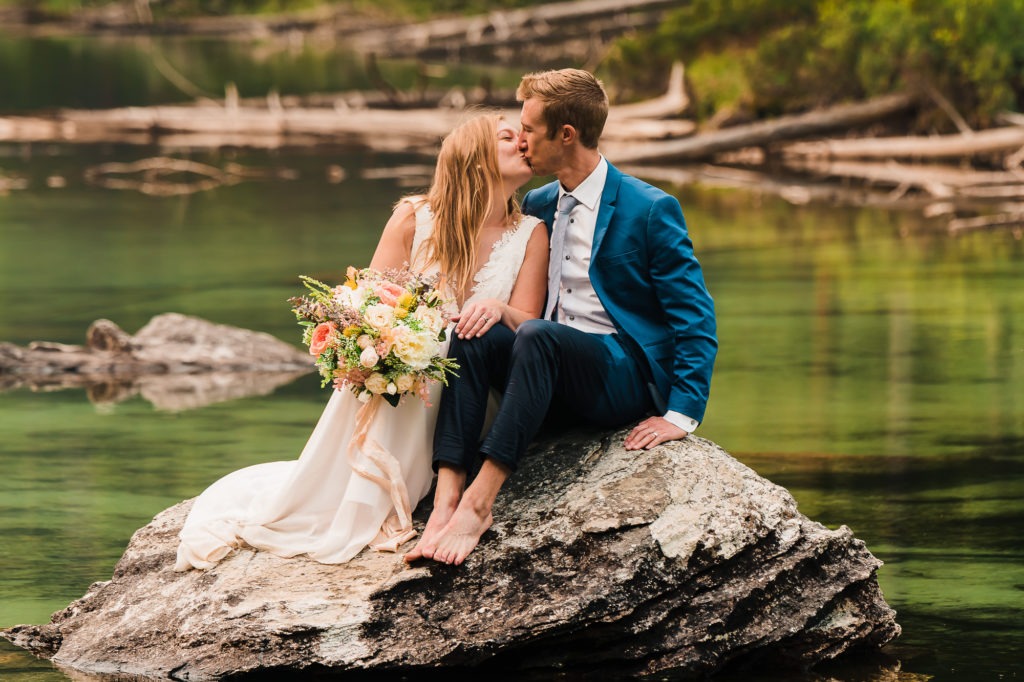The couple share a kiss as they sit on a rock in the middle of a lake, barefoot after walking out.