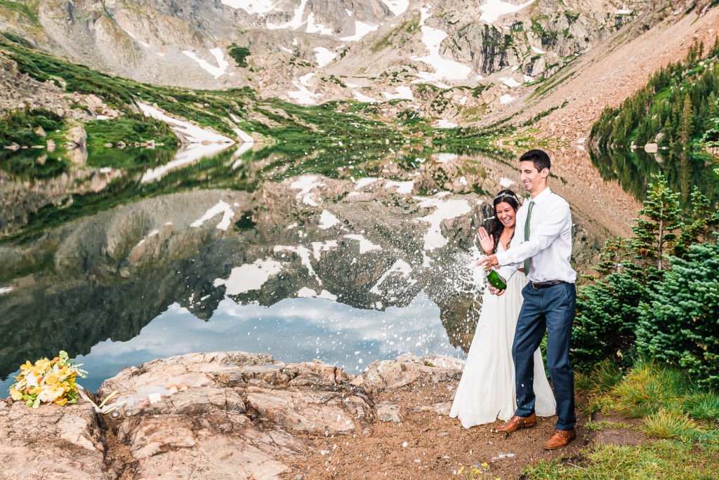 Colorado elopement in the mountains. The couple pop champagne to celebrate.