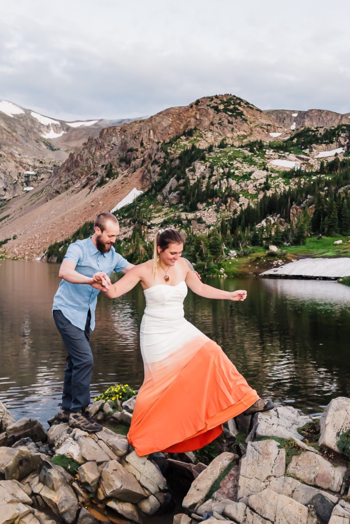 The couple scramble over rocks and have fun during their mountain engagement session.