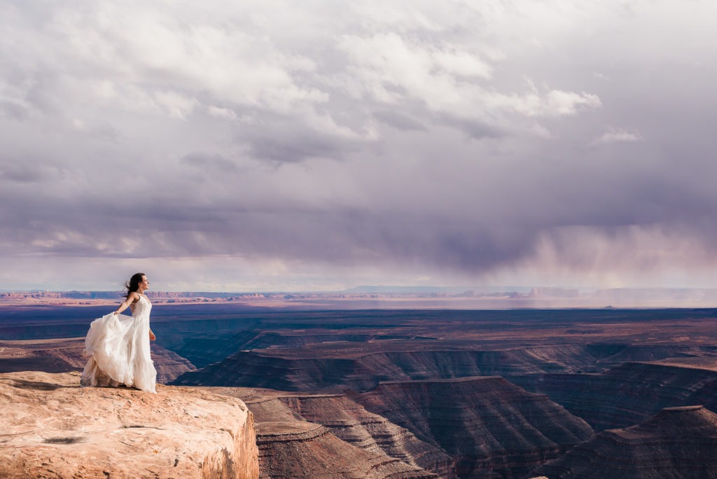 A badass bride with a super flowy wedding dress looks out over the canyons of Moab.