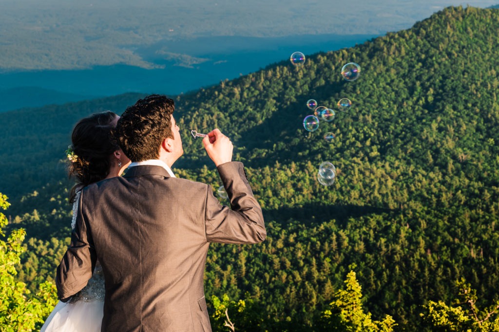 To celebrate their anniversary vow renewal, the couple blows bubbles over the green mountains.