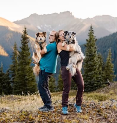 Chad and Vanessa stand back to back while holding their pups.