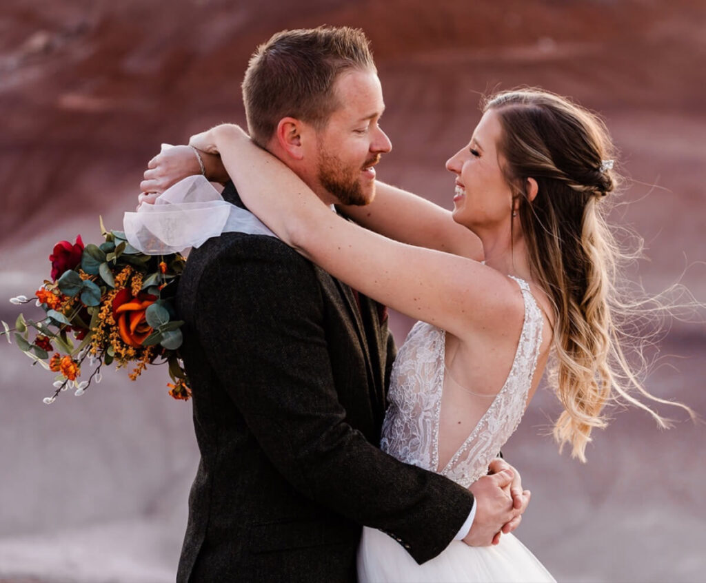 A couple embraces one another surrounded by the Utah rocky landscapes.
