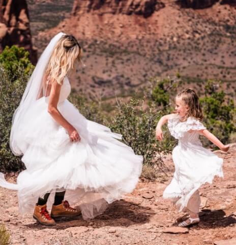 A person in a dress dances with a child in the desert.