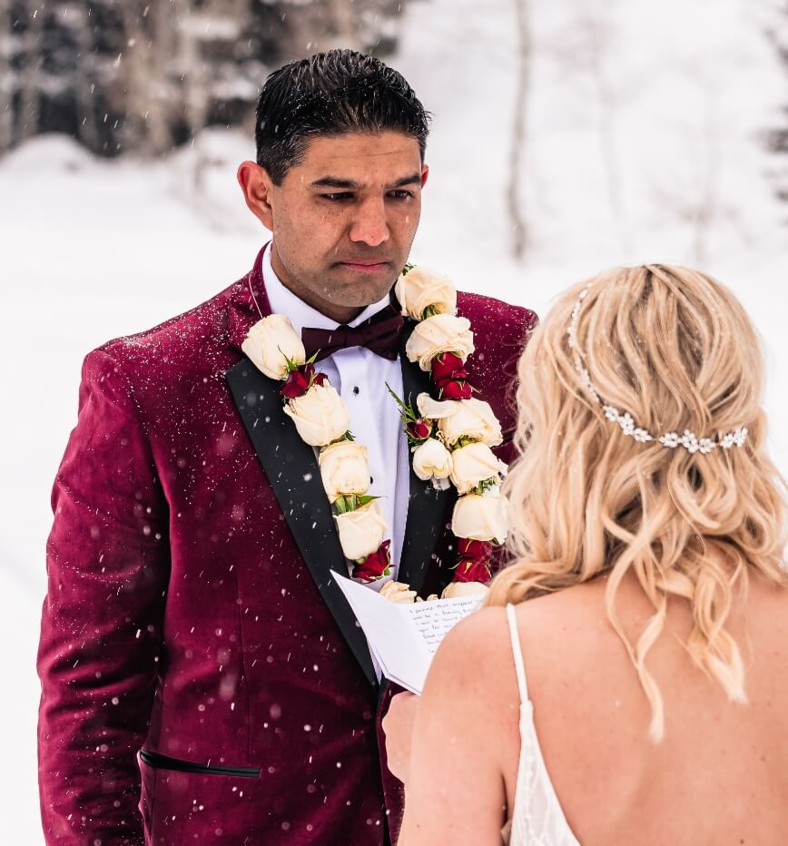 A person looking at their partner as they read their vows and snow lightly falls over them