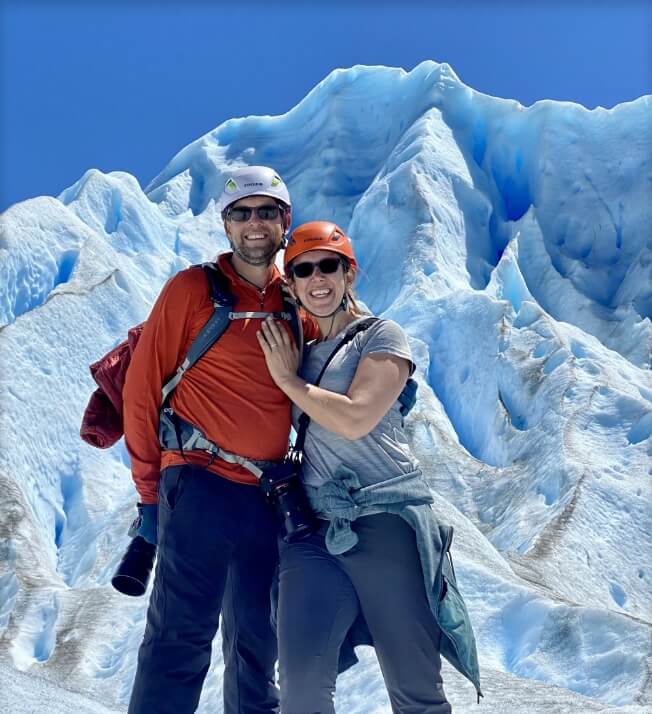 Chad and Vanessa smile in front of an ice mountain.