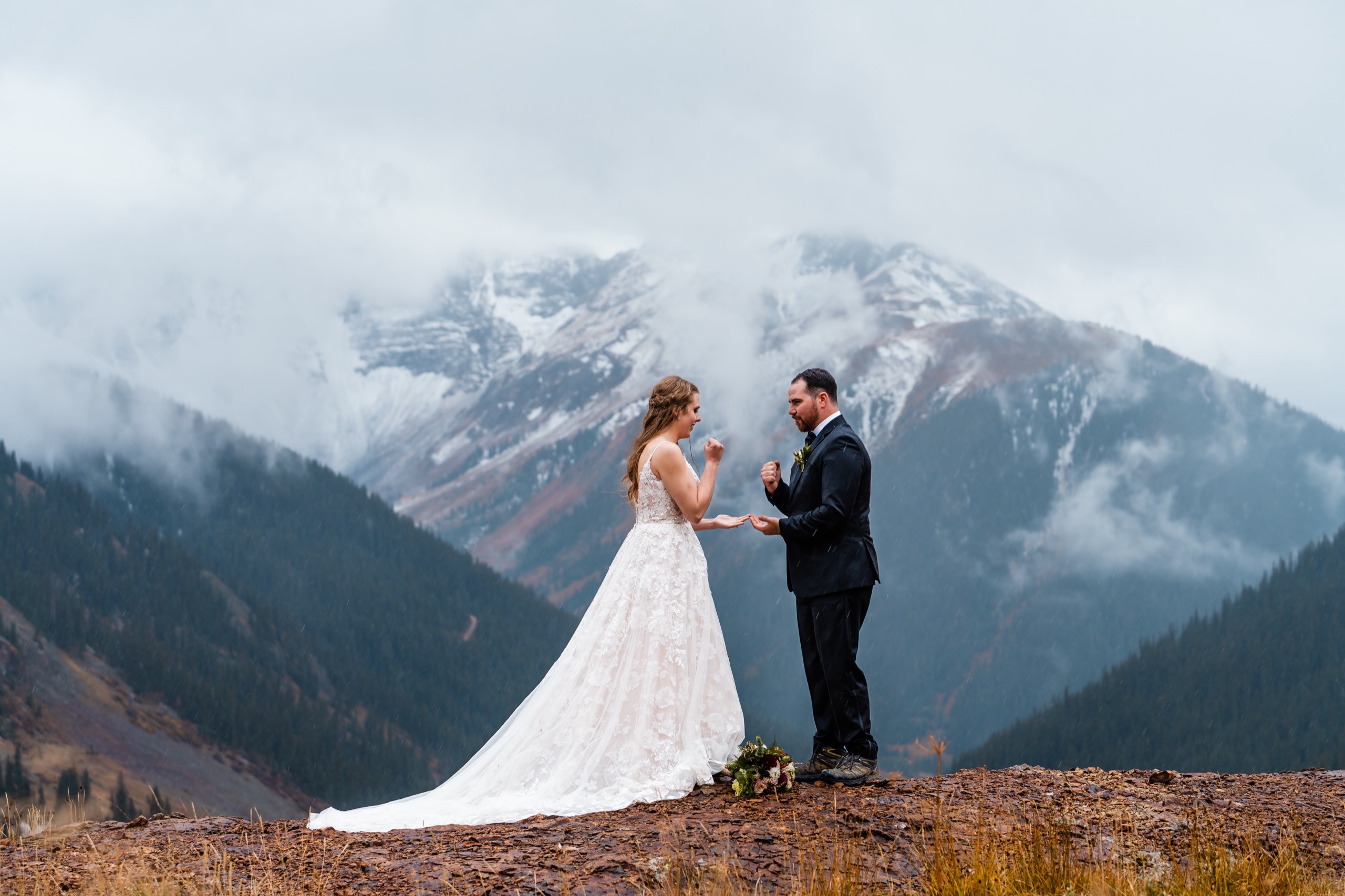 A newlywed couple playing rock, paper, scissors on a mountain overlook