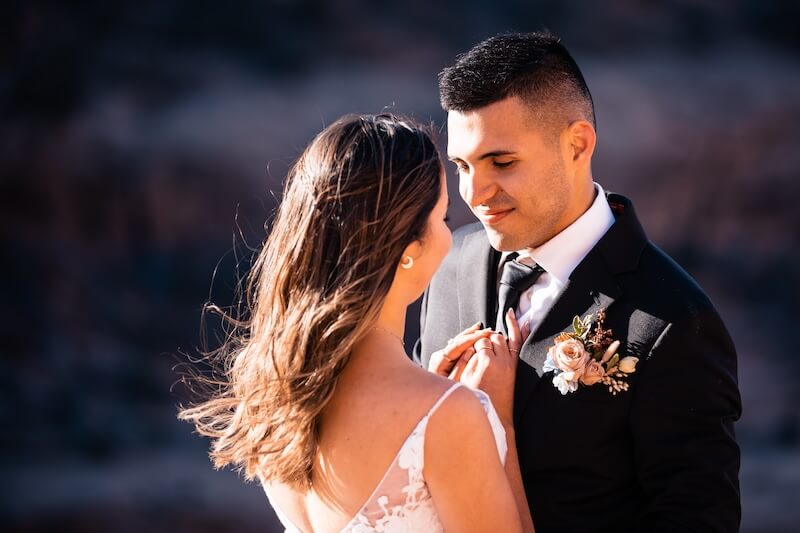 Two people lean in closely to speak to one another in their wedding clothes.