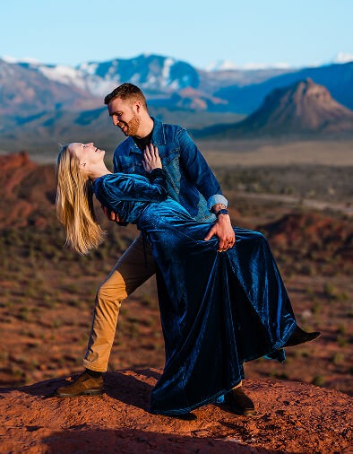 A person dipping their partner as they laugh and smile in the mountains