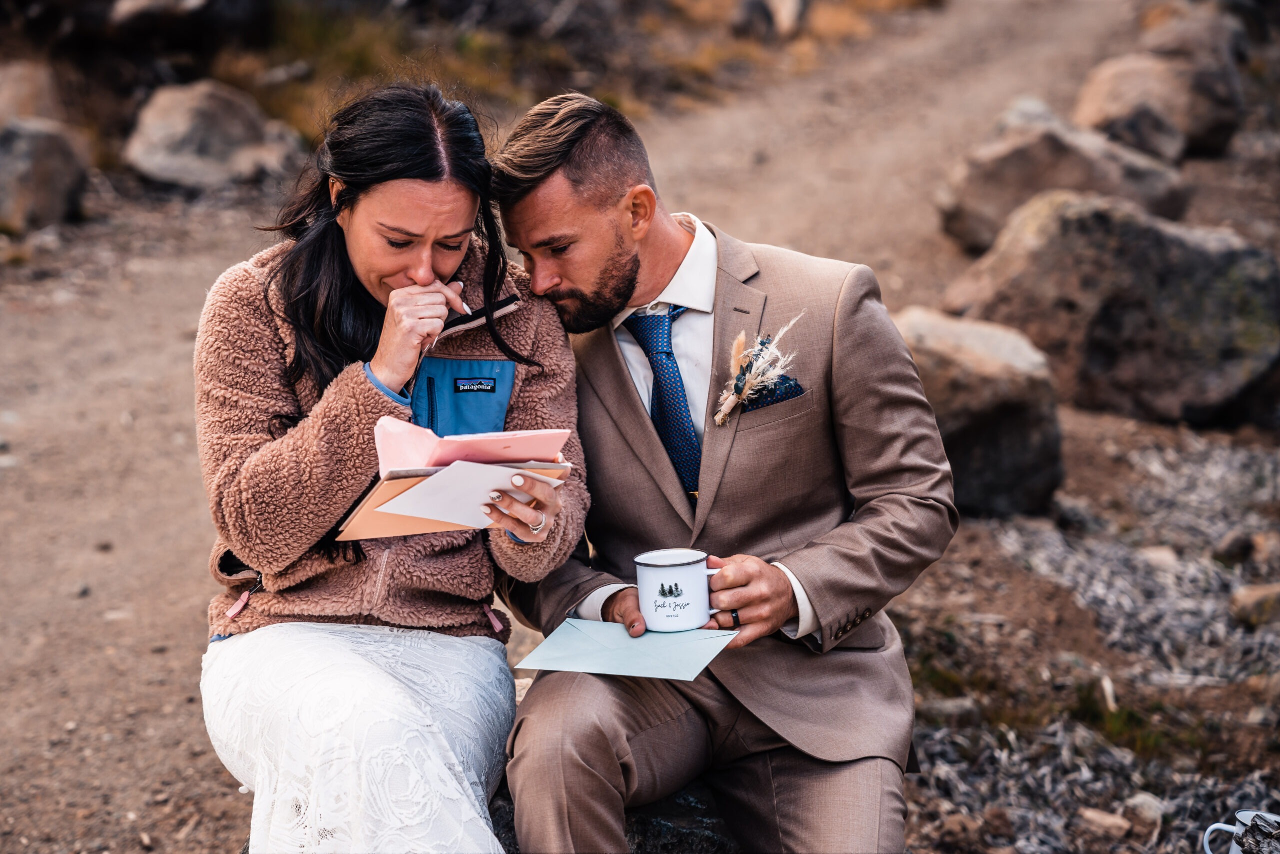 A couple leans into one another while reading notes from envelopes, one of them crying.